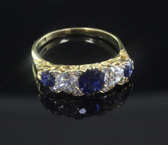 A mid 20th century 18ct gold and graduated five stone sapphire and diamond half hoop ring, size P.
